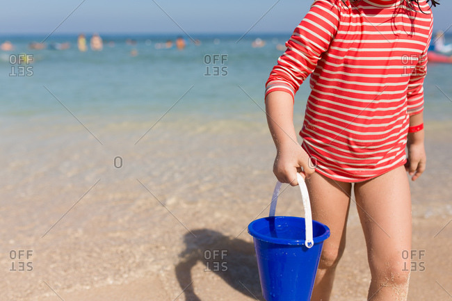 Girl carrying a bucket of water at the beach