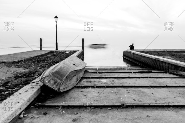 Man watches the passage of a boat in the boat launch at Burano lagoon, Venice, Italy