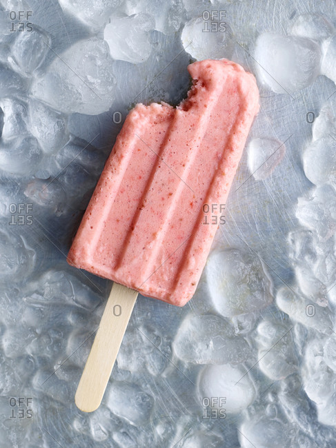 A strawberry popsicle with a bite missing