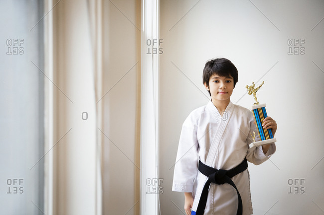 Boy in martial arts outfit with trophy