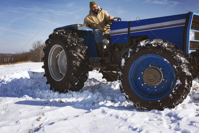 Man driving blue tractor through the snow