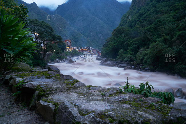 River flowing over rocks near a city at dusk
