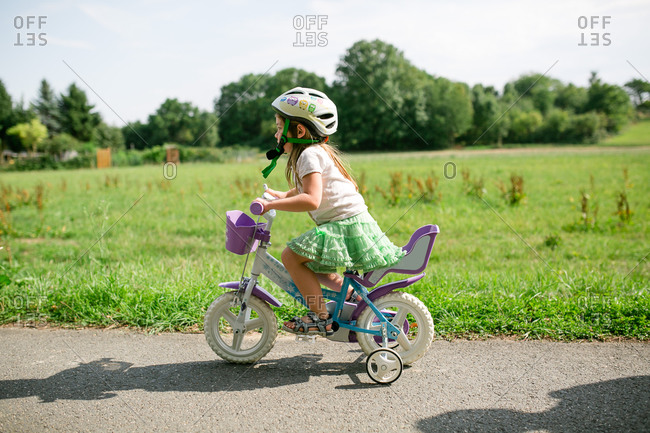 Little girl riding a bike with training wheels