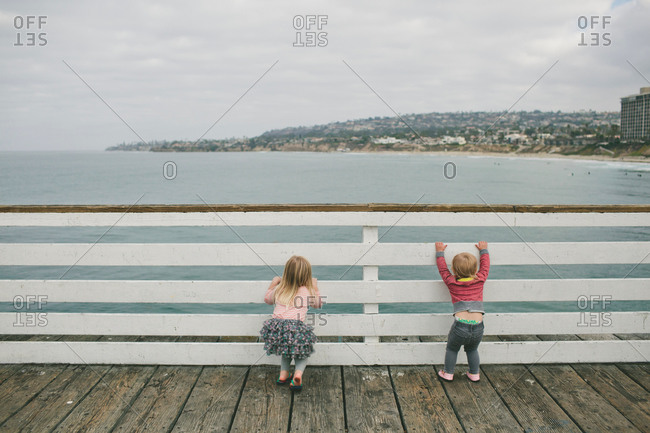Two small children looking through railing on a boardwalk