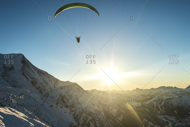 Paraglider and the sun over mountains in the French Alps