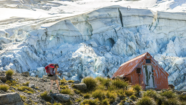 Backpacker walking toward a mountain hiker\'s hut at Aoraki Mount Cook, New Zealand