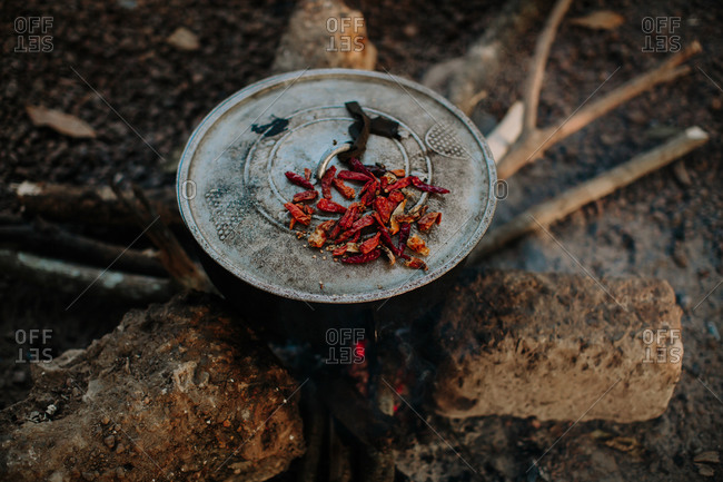 Dried chili pods on top of a lidded pot over a fire