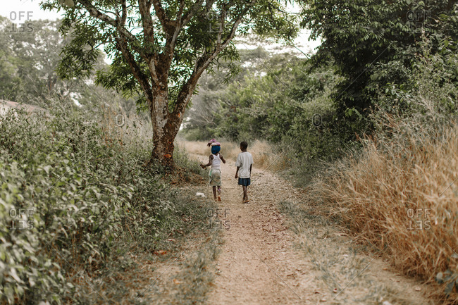 Two children walking down a dirt pathway in the rural countryside of Sierra Leone