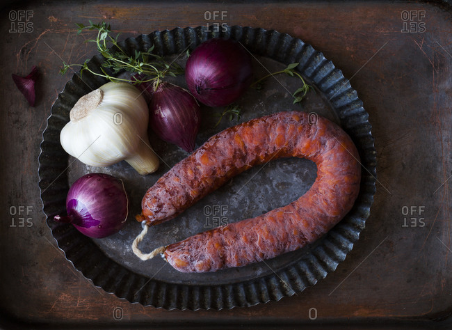Platter of chorizo sausage with red onions and garlic bulb
