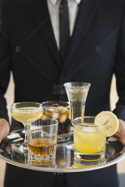 Close up of  waiter holding tray of drinks of yellow drinks