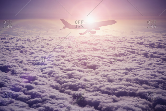 Silhouette of airplane flying over clouds