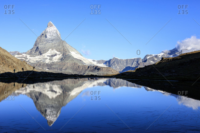Hikers by Matterhorn reflected in lake, Switzerland