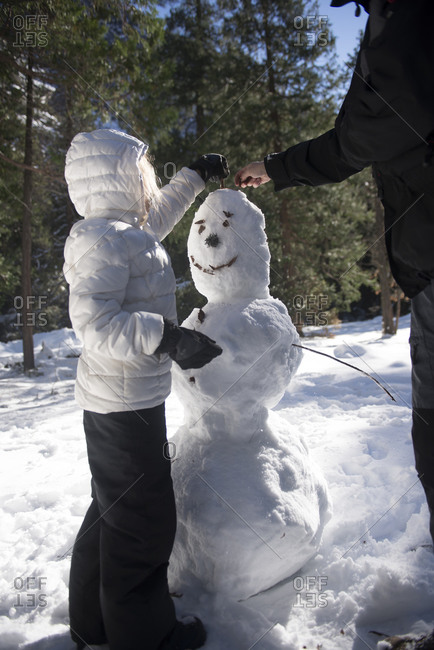 Father and daughter adding hair to a snowman