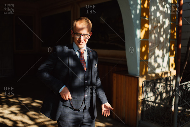 Groom tucking his pocket watch into his suit\'s vest pocket