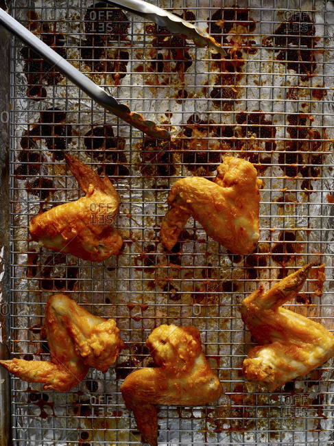 Overhead view of buffalo chicken wings on a wire cooking grate