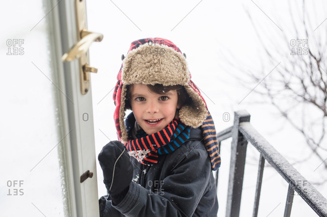 Boy opening front door to come inside during snowy weather