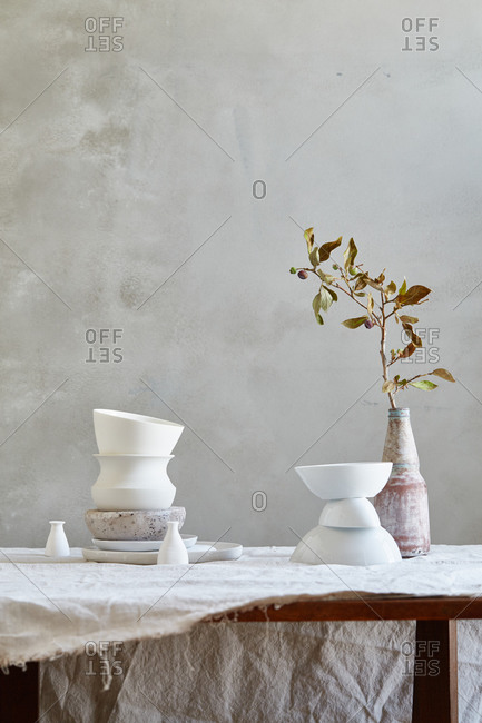 White ceramics, fig branch and muslin cloth on a table
