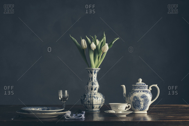 Still life of a vase of tulips and place setting on a wood table