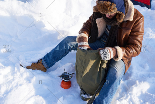 Man sitting in the snow unpacking food items