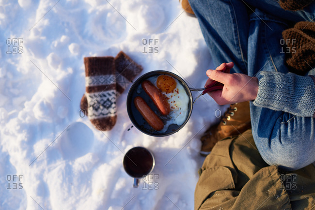 Man holding a pot with breakfast in the snow