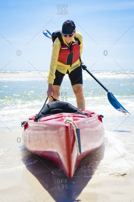 Woman pulling a kayak into the ocean