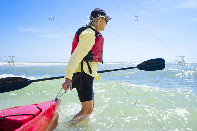 Woman pulling a kayak in the surf