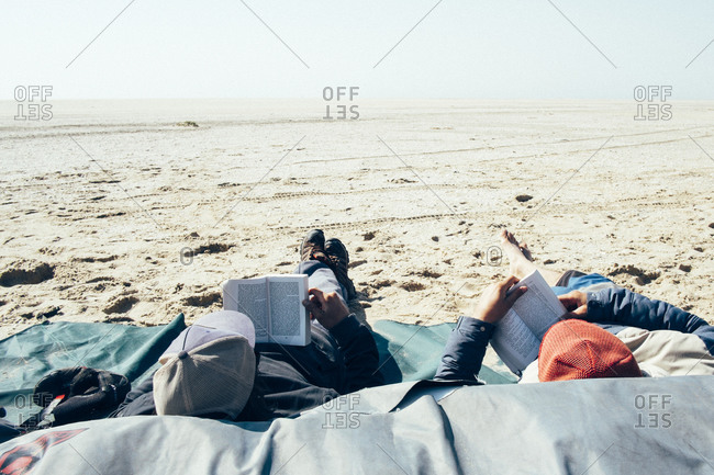 Two boys read a book while chilling on the beach