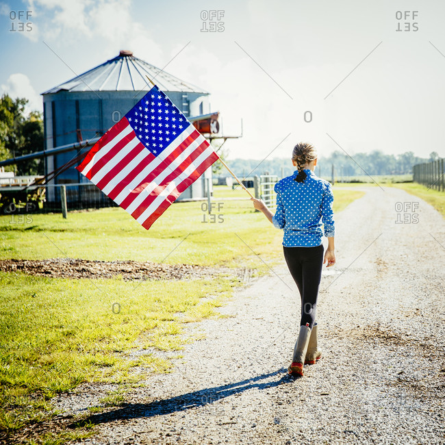 Girl waving American flag on farm
