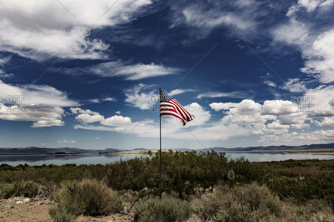 American flag flying near a mountain lake