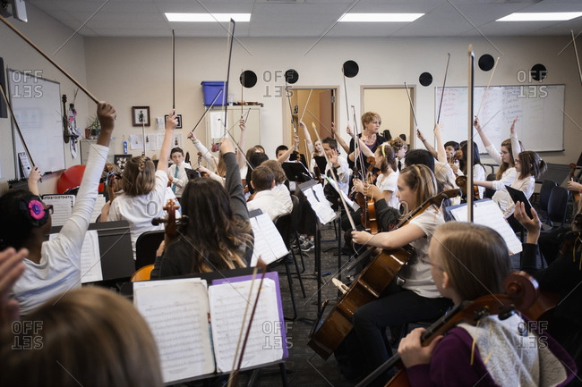Students raising instrument bows in music class
