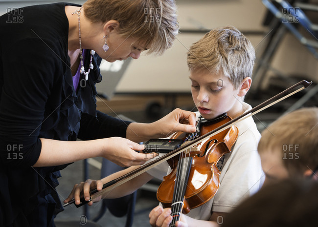 Teacher tuning students instrument in music class
