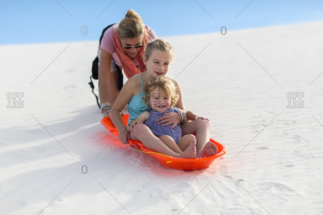 Mother and children sledding on sand dune