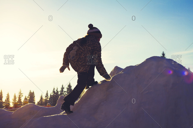 Girl climbing snowy hill