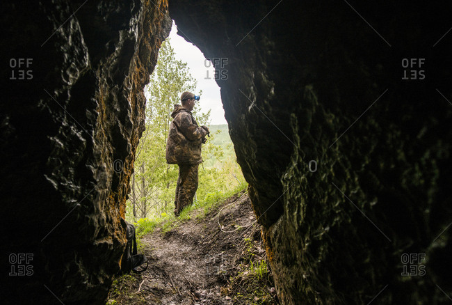 Man standing outside rock formation cave