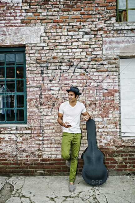 Musician with guitar case using cell phone