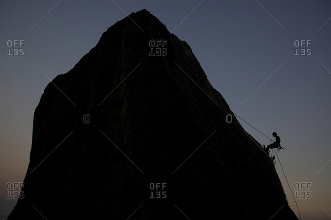 Silhouette of rock climber climbing around Sugar Loaf Mountain, Rio de Janeiro, Brazil