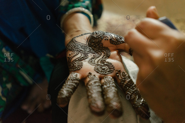 Woman receiving intricate henna decorative painting on the palm of her hand