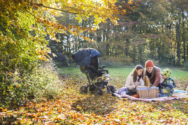 Mother and children looking in picnic basket in autumn