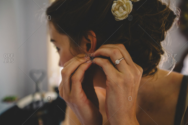 Bride putting on earrings before her wedding
