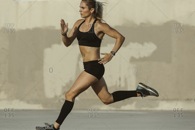 Athletic woman in shorts and a sports bra running outside
