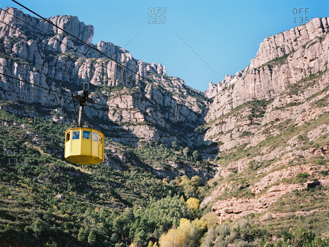 Yellow gondola traveling along a steep mountain ridge