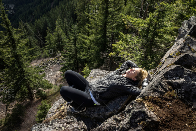 Woman lying on rock on mountaintop