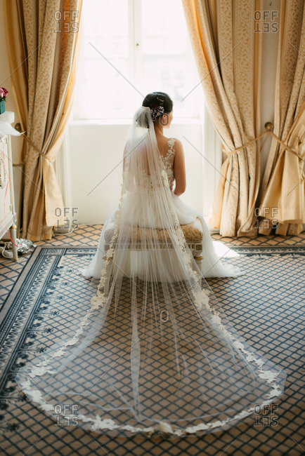 Back view of elegant seated bride with veil spread out behind her
