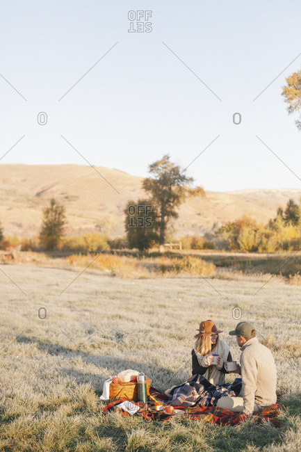A couple having a picnic in a rural meadow in late afternoon