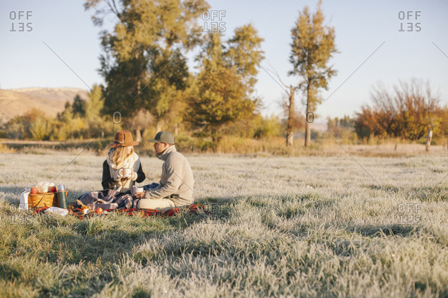 Friends having a picnic in a rural meadow in late afternoon