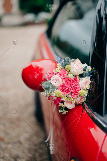 Flower bouquet attached to side mirror of red car