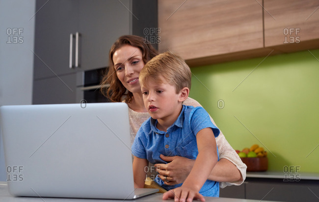 Mother and son looking at a laptop computer in the kitchen
