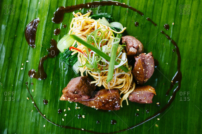 Seared duck breast and noodles served on a banana leaf