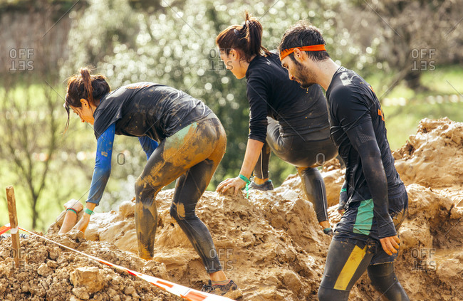 Extreme obstacle race team climbing a muddy hill