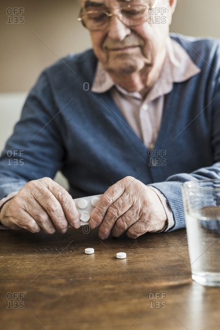 Senior man taking tablets out of blister pack, close-up